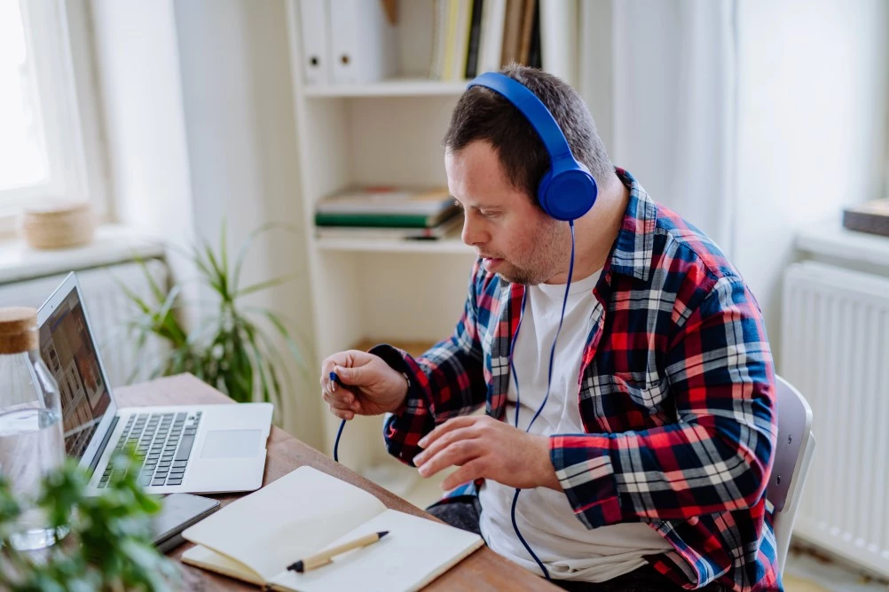 Man with down syndrome looking at laptop with headphones on