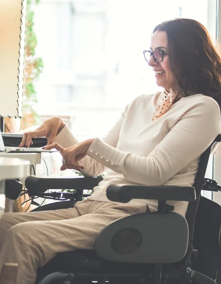 Disabled woman in wheelchair typing on laptop
